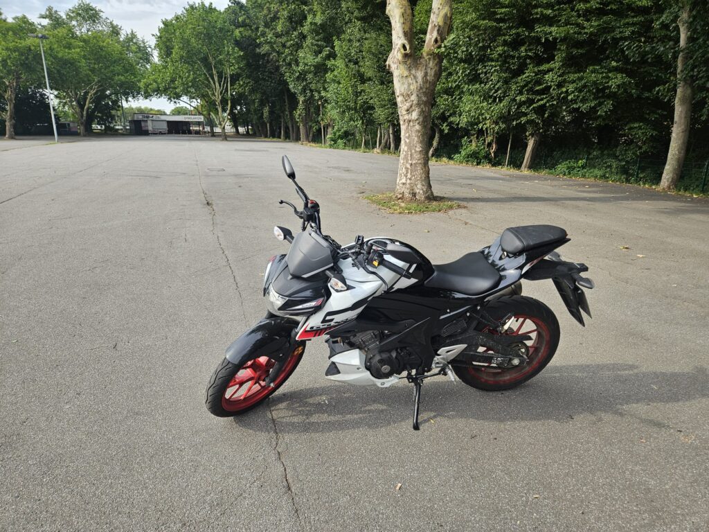 Ein schwarzes Motorrad mit roten Rädern steht auf einem leeren Parkplatz.