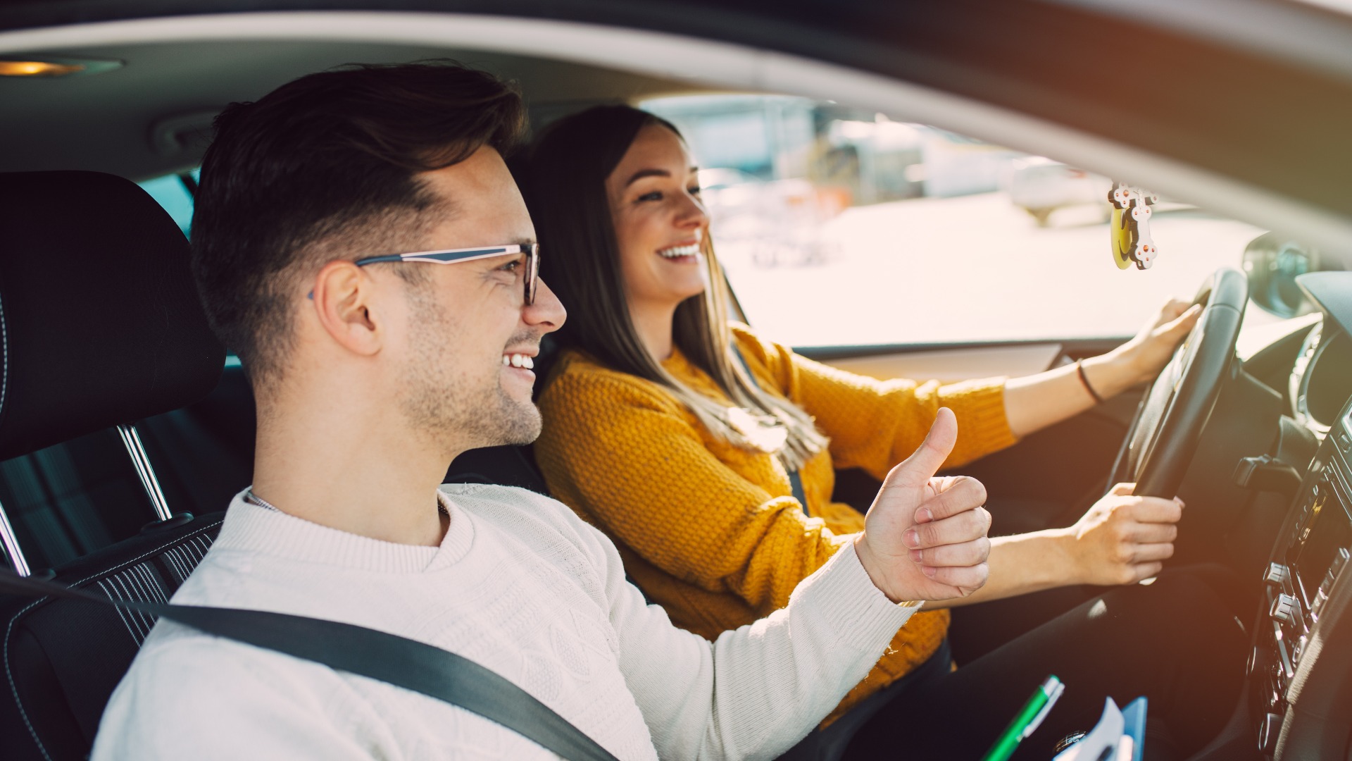 Fahrschule oder Prüfung. Schöne junge schwangere Frau, die zusammen mit ihrem Fahrlehrer das Autofahren lernt.